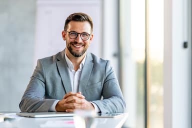 Man in suit smiling at off-camera client Man in suit smiling at off-camera client