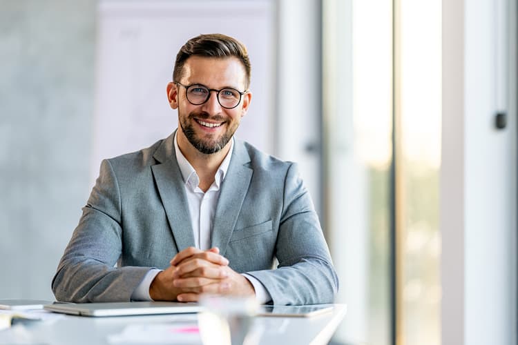 Man in suit smiling at off-camera client Man in suit smiling at off-camera client