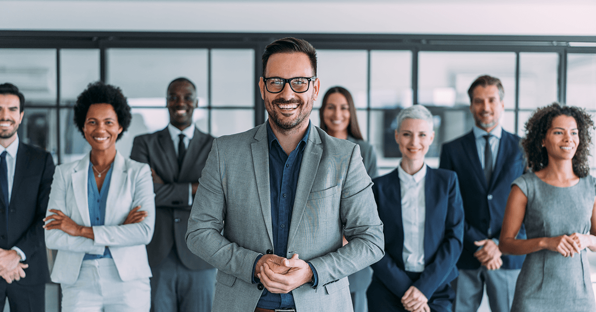 A Smiling Businessman with Colleagues in the Background Representing the Texas REALTOR® Leadership Team Event
