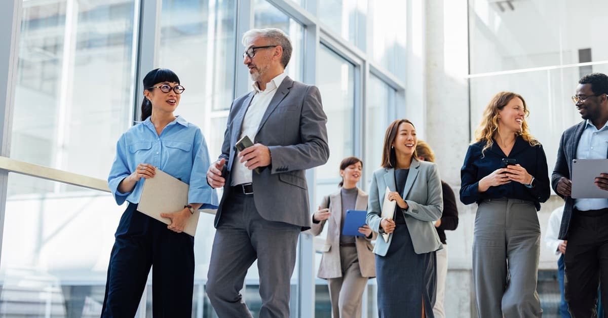 Office Workers Walking Through a Windowed Hallway Representing the ICE Experience in Las Vegas, NV