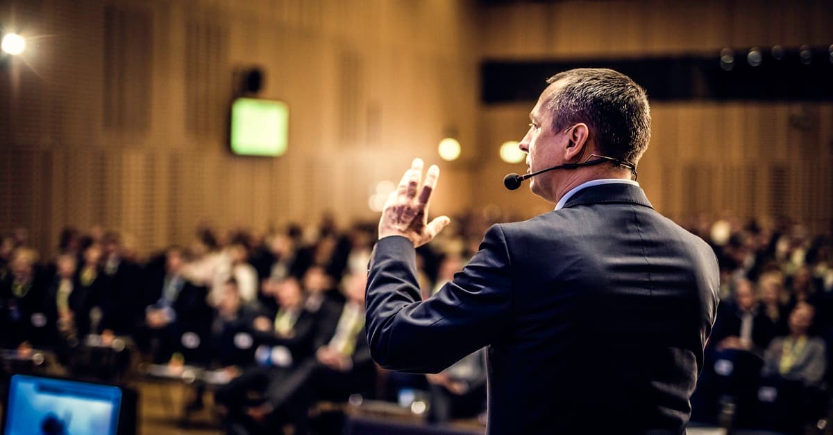 View from Behind of a Speaker with a Headset Microphone Representing the Leading RE Conference Week in Las Vegas, NV