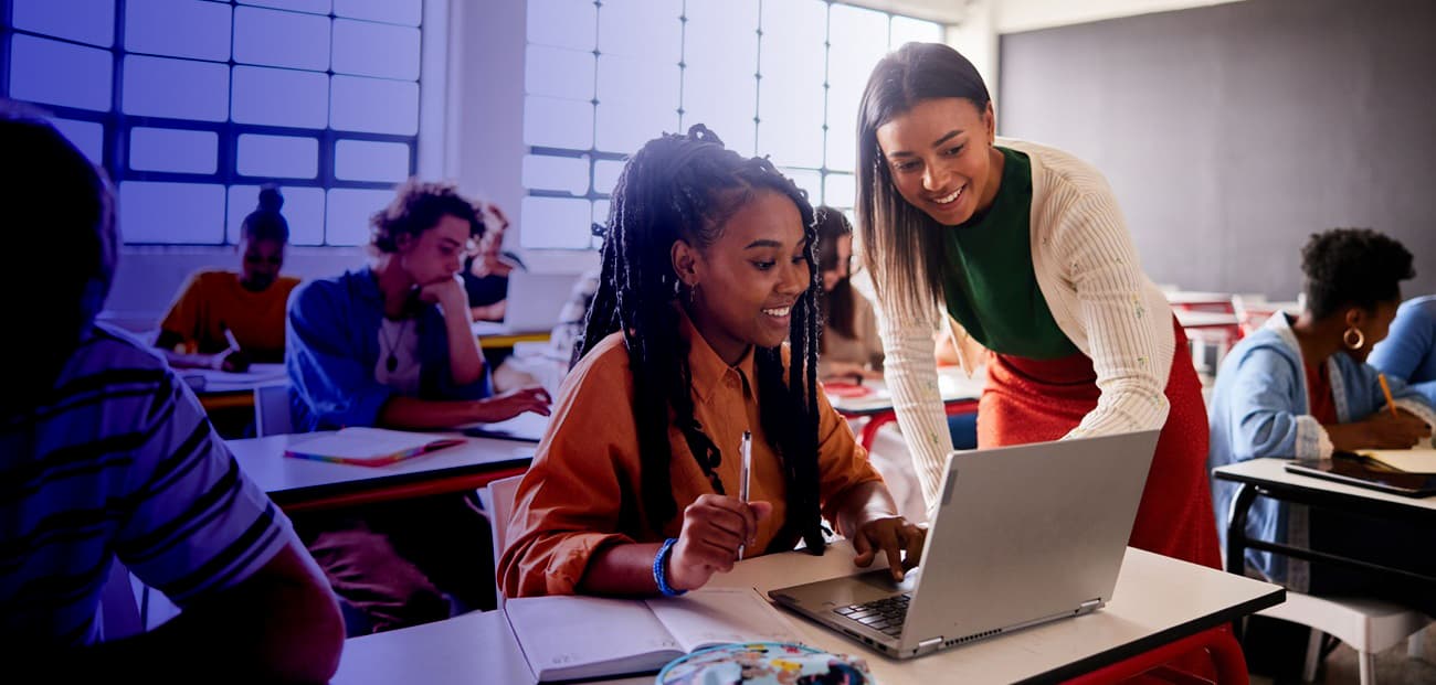 Teacher working with high school student at desk