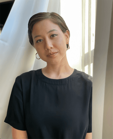 A photo of Iona Brannon in a black shirt with a small, closed-mouth smile