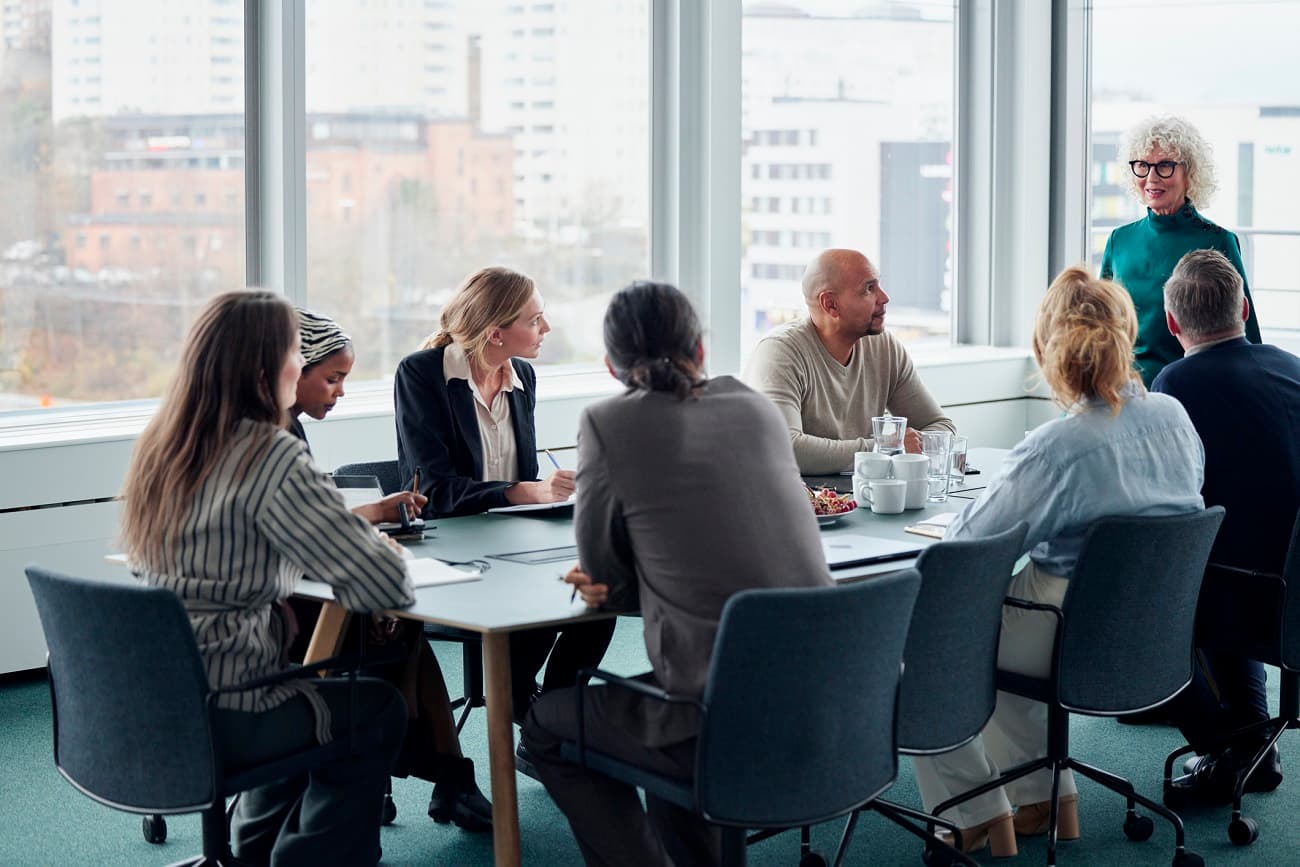 People sitting at the table during business meeting listening to woman standing up