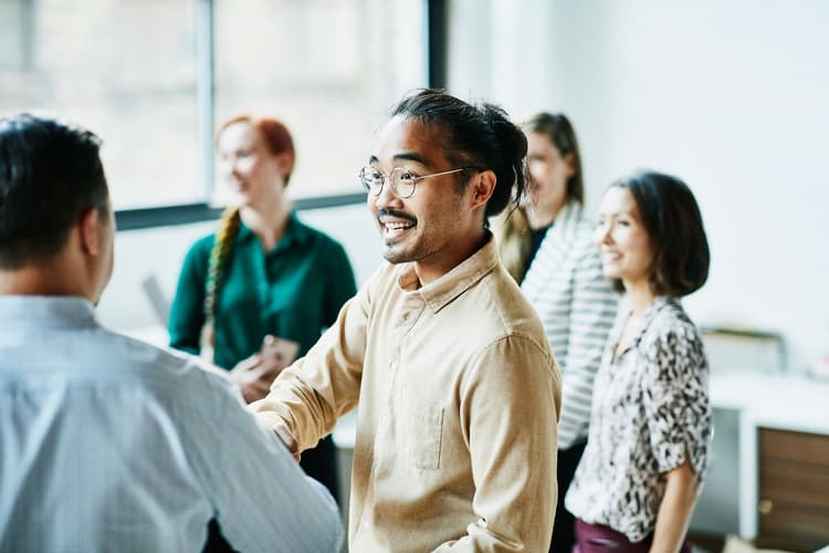Businessman shaking hands with colleagues in a bright office Businessman shaking hands with colleagues in a bright office