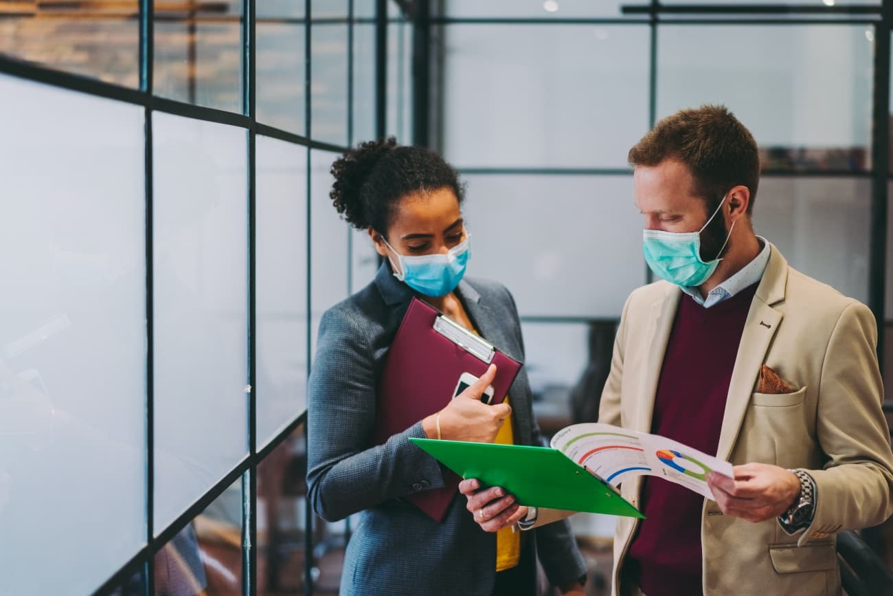 two masked colleagues working in office
