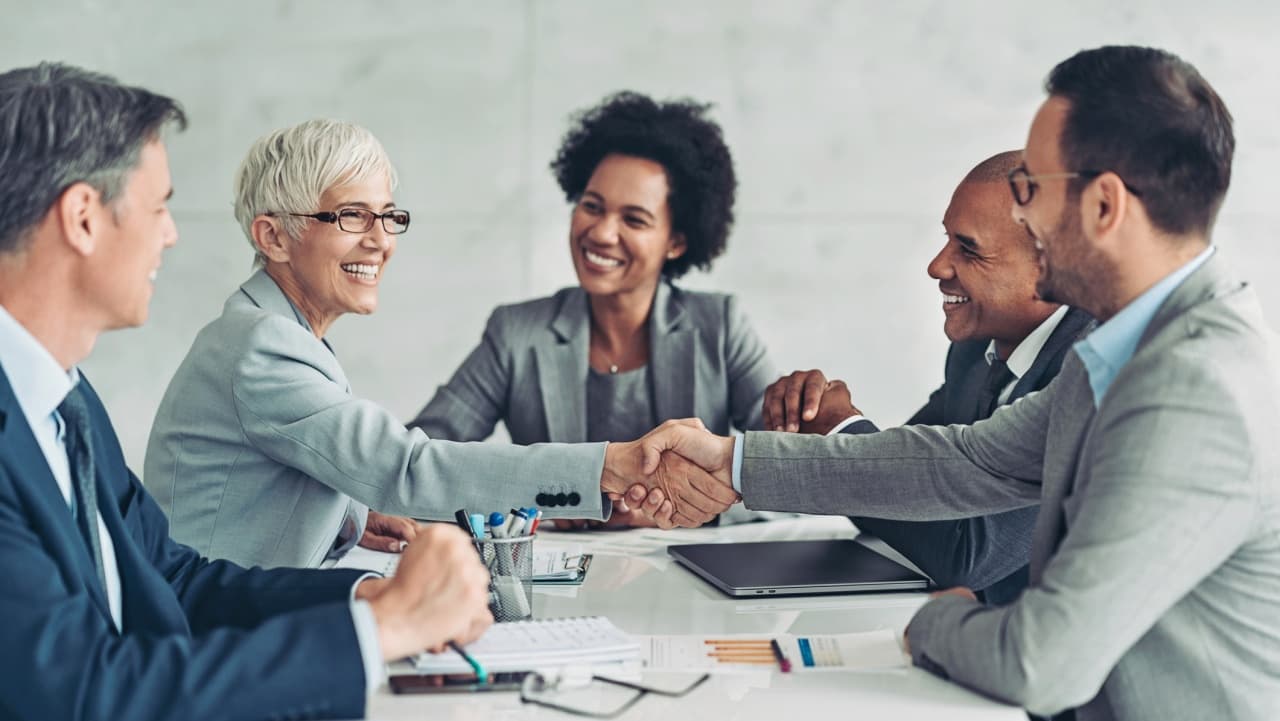 Business people shaking hands across a table - risk management antitrust