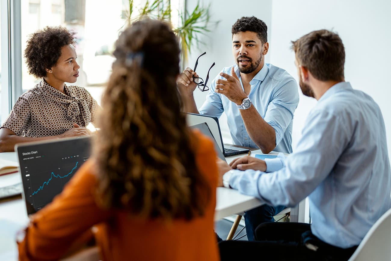 Group of young modern people in smart casual wear discussing business while sitting in the creative office