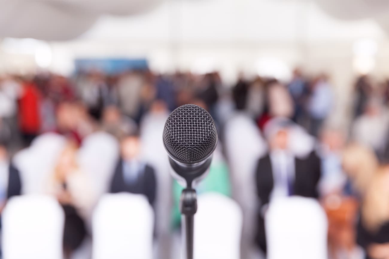 Microphone in front of blurred conference audience Microphone in front of blurred conference audience