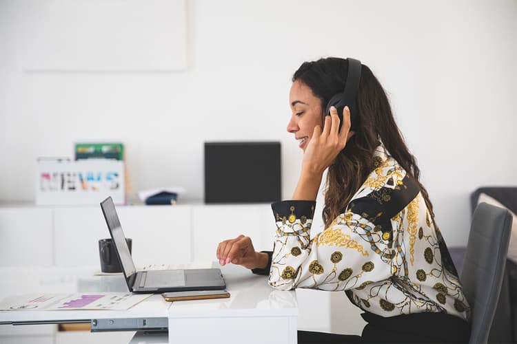 Professional woman at a laptop wearing headphones Professional woman at a laptop wearing headphones