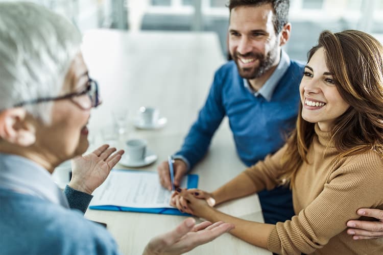 Smiling couple talking to a woman in an office Smiling couple talking to a woman in an office