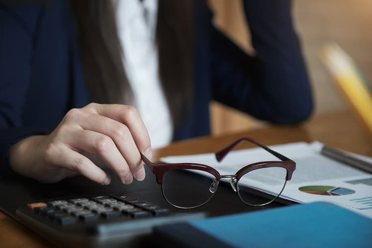 Woman in navy suit with glasses and calculator Woman in navy suit with glasses and calculator