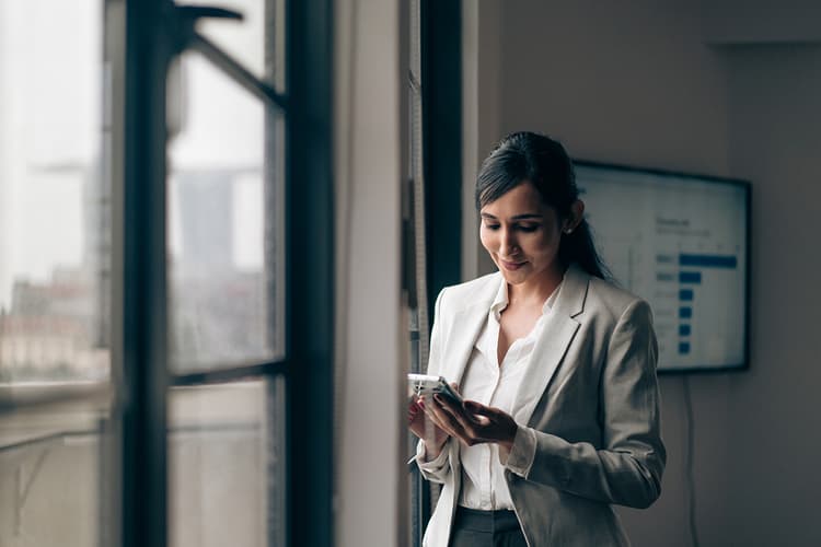 Woman wearing a suit looking at a cell phone in a conference room Woman wearing a suit looking at a cell phone in a conference room