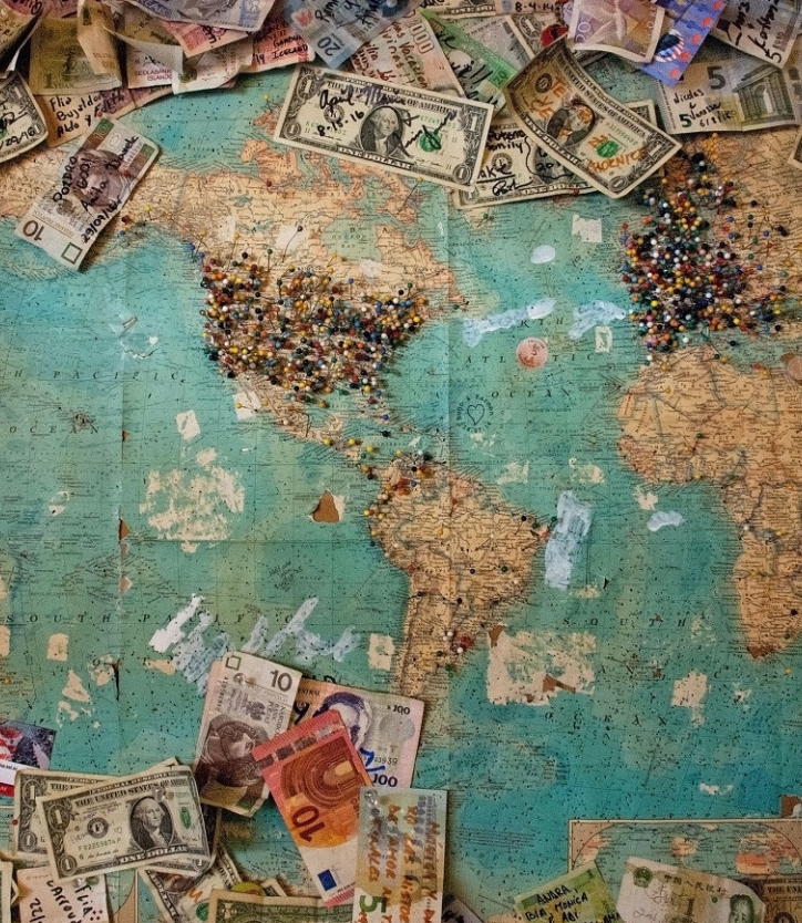 World map with bills from different currencies spread on it