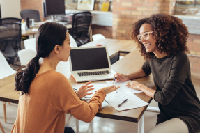 Two business women discussing paperwork in a modern office