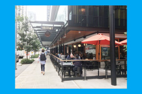 A corner restaurant with outdoor sitting next to a sidewalk
