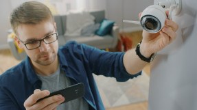 Man setting up security camera with smart phone