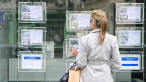 woman viewing real estate listing posted to real estate office window