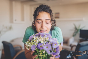 young woman smelling fresh flowers at home
