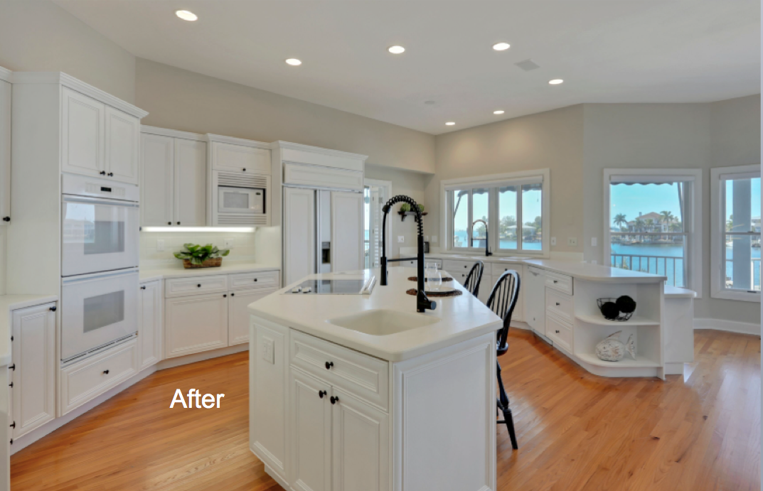 A Kitchen with island, and white cabinets with light colored hardwood floor