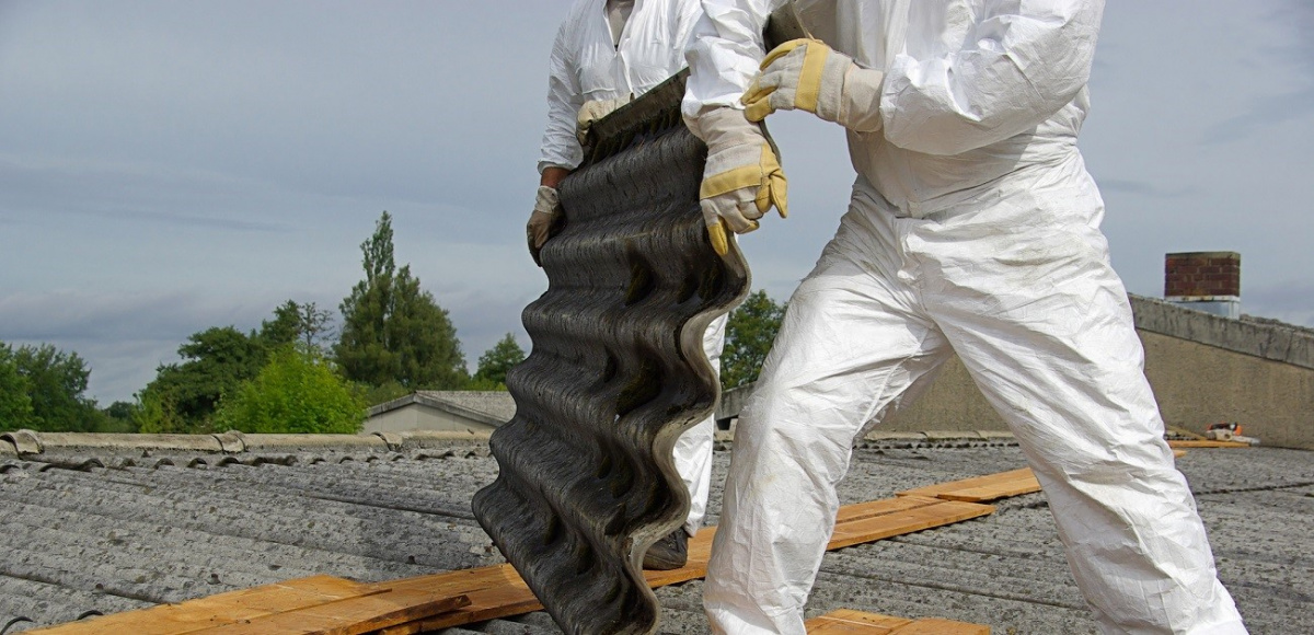 workers in hazmat suits handling asbestos on roof