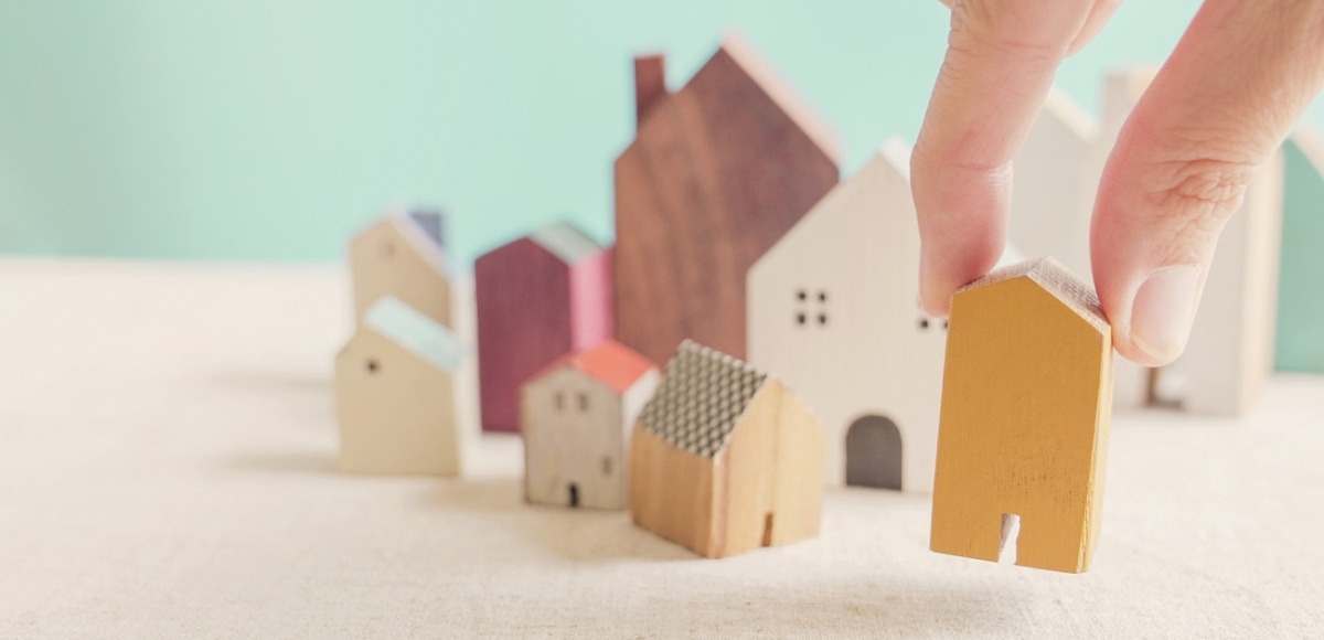 Hand choosing yellow miniature house