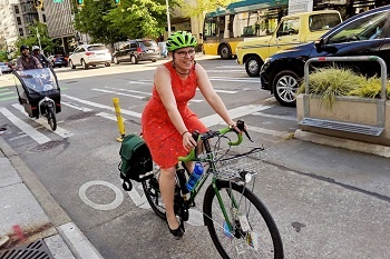 A woman in a red dress riding a bycicle on a bike path