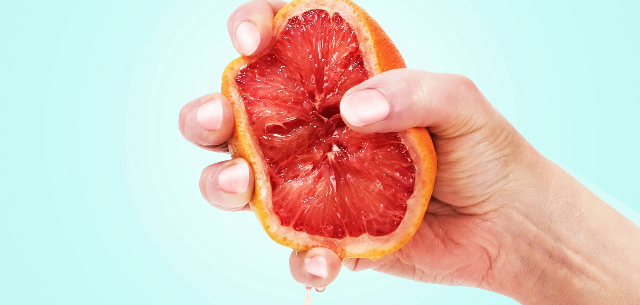 hand squeezing orange or grapefruit