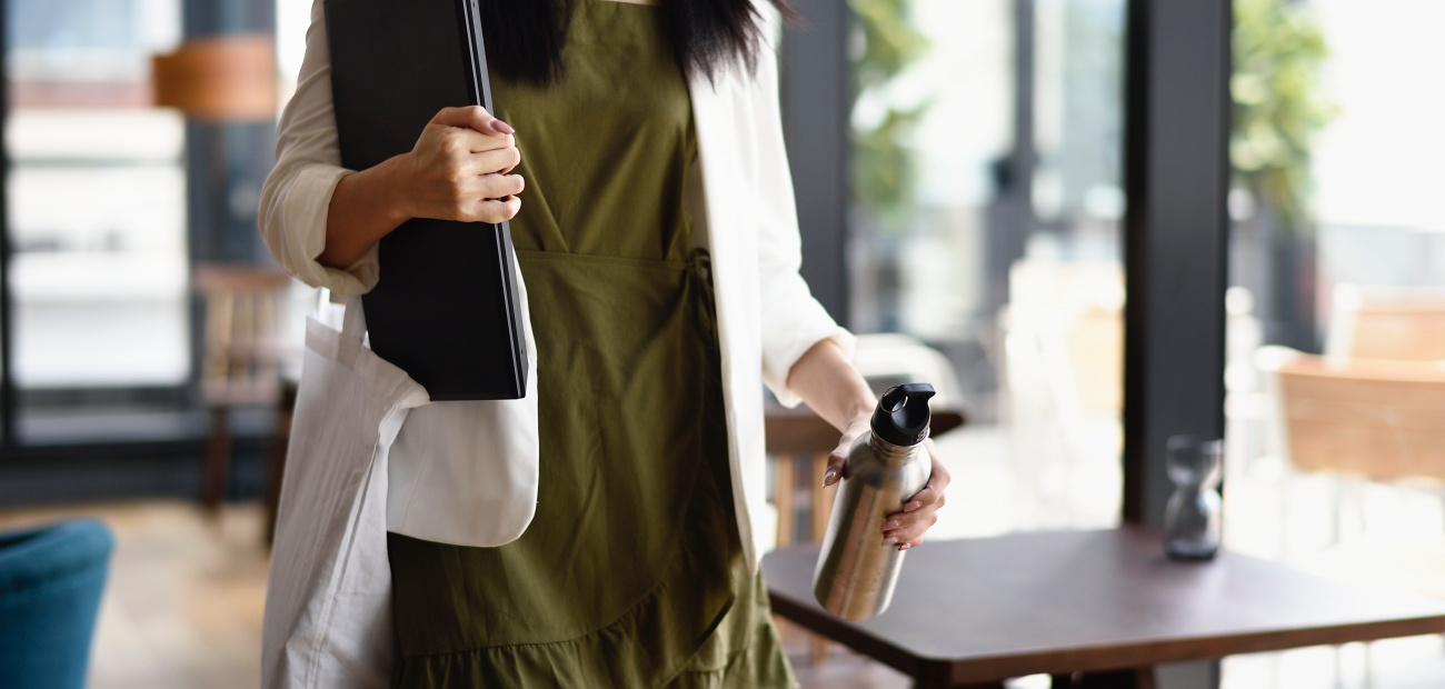 woman carrying laptop through cafe