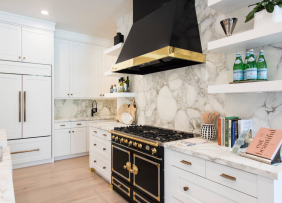 A kitchen with black stove and black exhaust hood with brass fittings and trim
