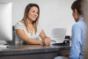 Smiling woman showing contract to client at desk