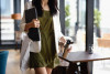 woman carrying laptop through cafe
