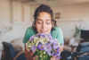 young woman smelling fresh flowers at home