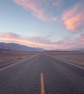 Straight road in desert at sunset